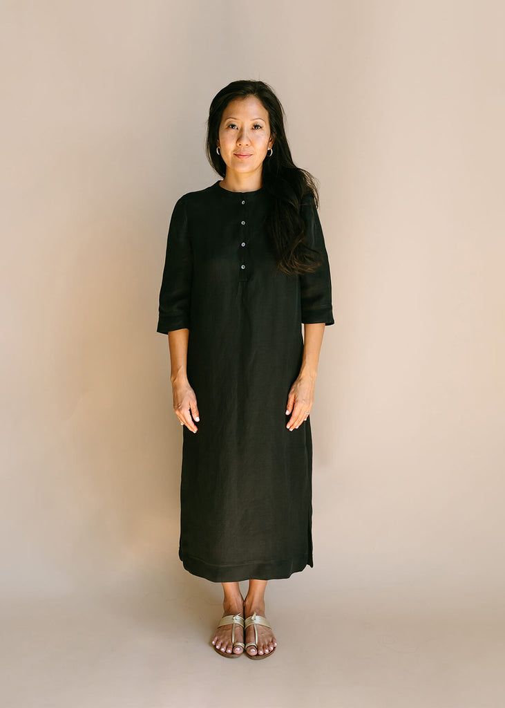 Woman wearing a Tunic style dress with pockets, and high side slits, in black.