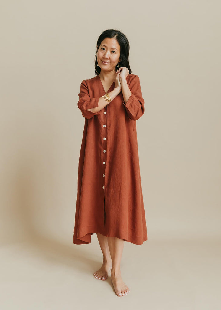 woman wearing the Sienna everyday buttonedshirtdress in burnt sienna with ¾ sleeves, a V-neck, an uneven hemline.