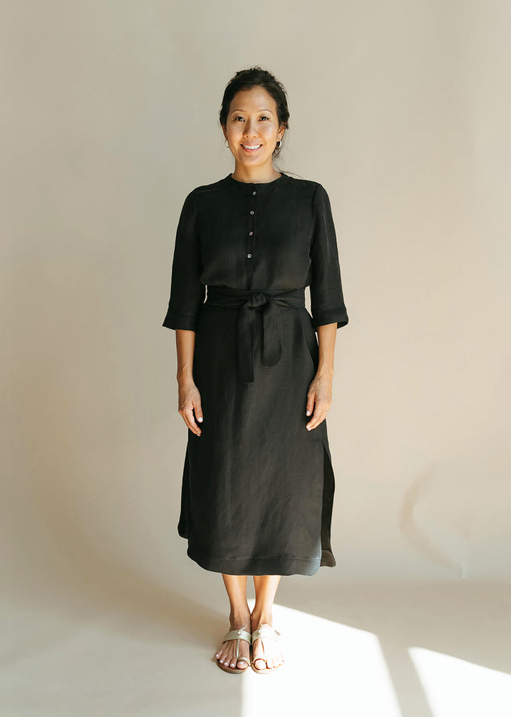 Woman wearing a Tunic style dress with pockets, a detached belt and high side slits, in black.