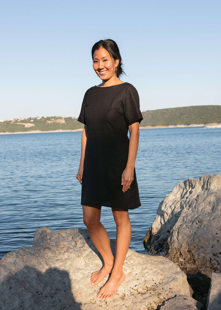 woman wearing a linen dress that hits above the knee, all black with three quarter length sleeves.