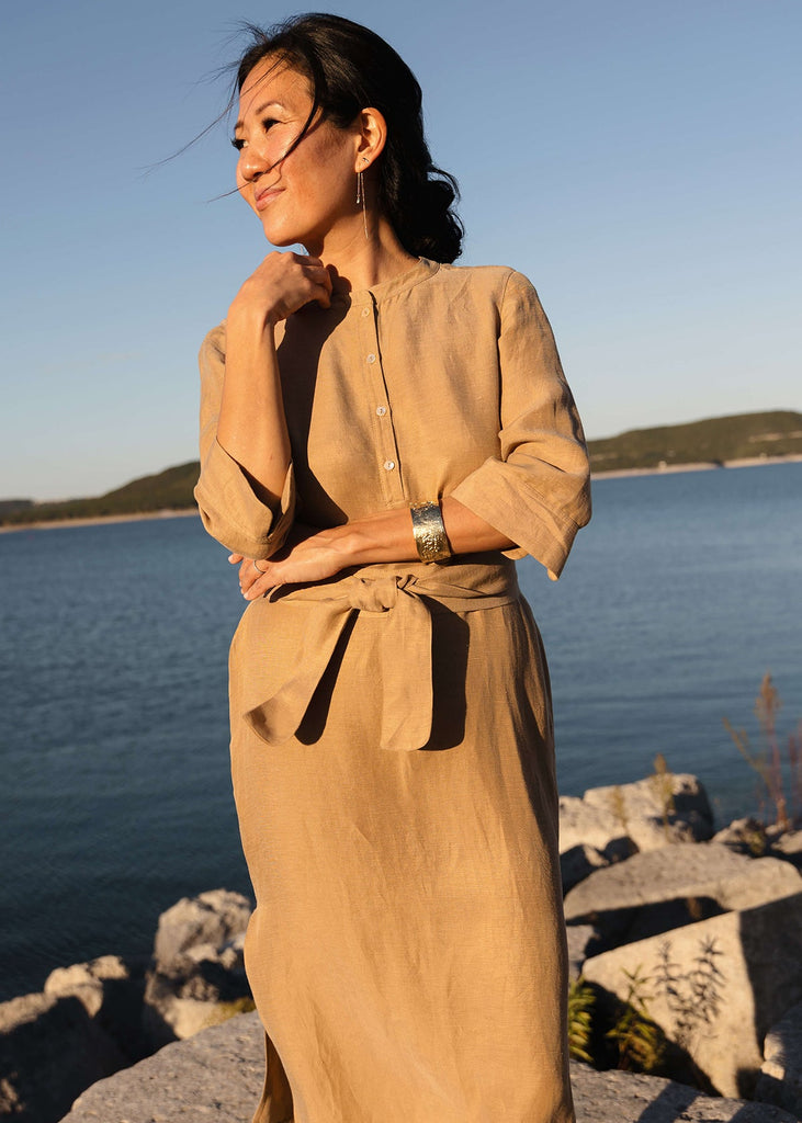 Woman wearing a Tunic style dress with pockets, a detached belt and high side slits, in a light brown camel color.