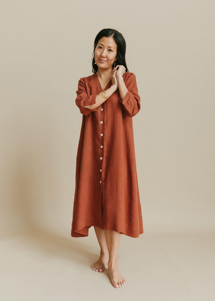 woman wearing the Sienna everyday buttonedshirtdress in burnt sienna with ¾ sleeves, a V-neck, an uneven hemline.