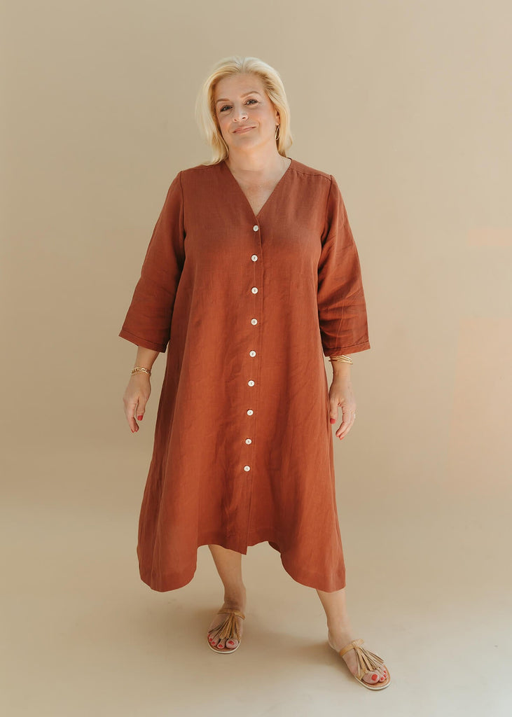 woman wearing the Sienna everyday buttoned shirtdress in burnt sienna with ¾ sleeves, a V-neck, an uneven hemline.