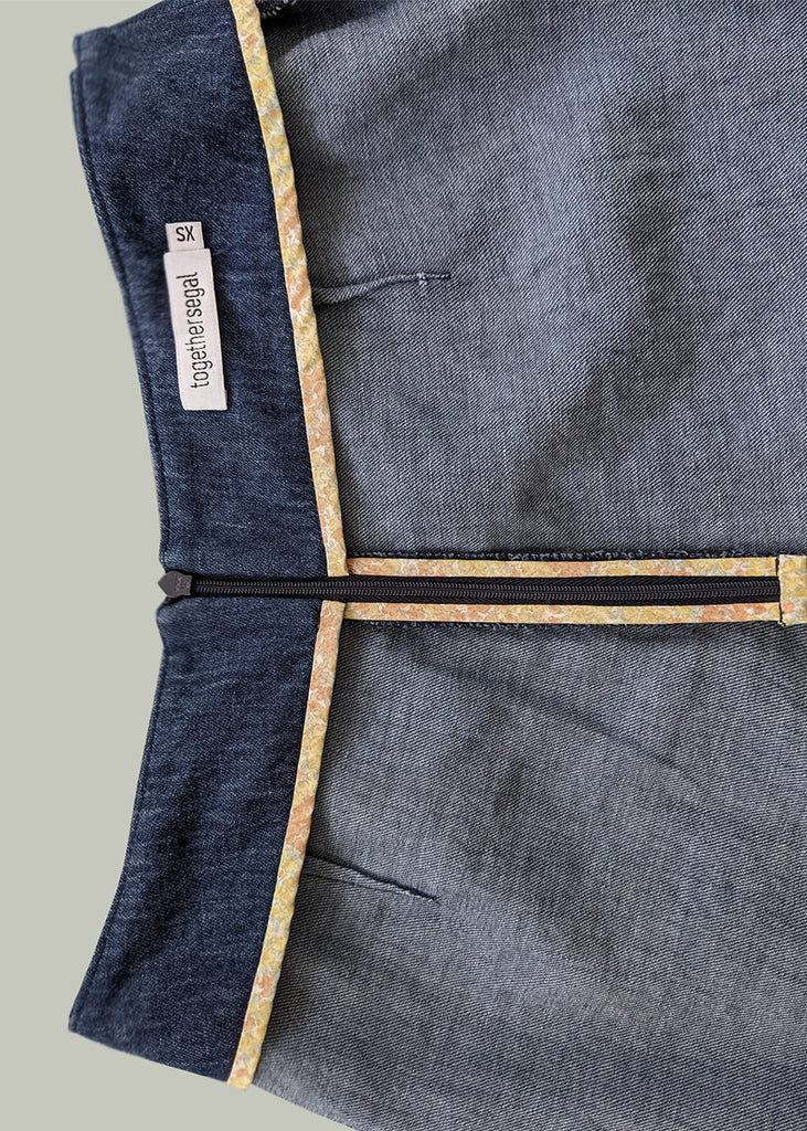 aerial view of the inside of a pair of dark blue pants, with a zipper, and a tag at the top.