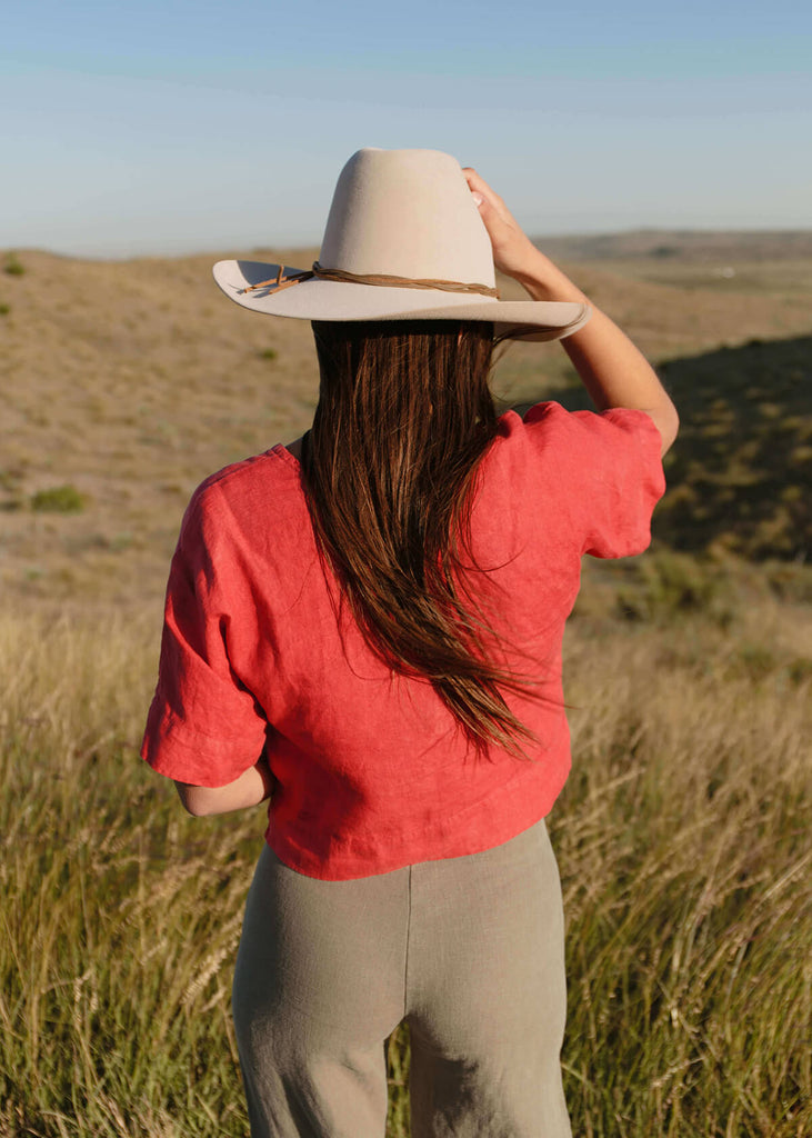 back view of woman wearing high-waisted, natural colored pants, with no back pockets.