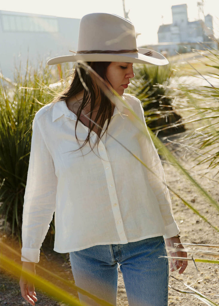 woman wearing a linen natural cream-colored button up shirt.